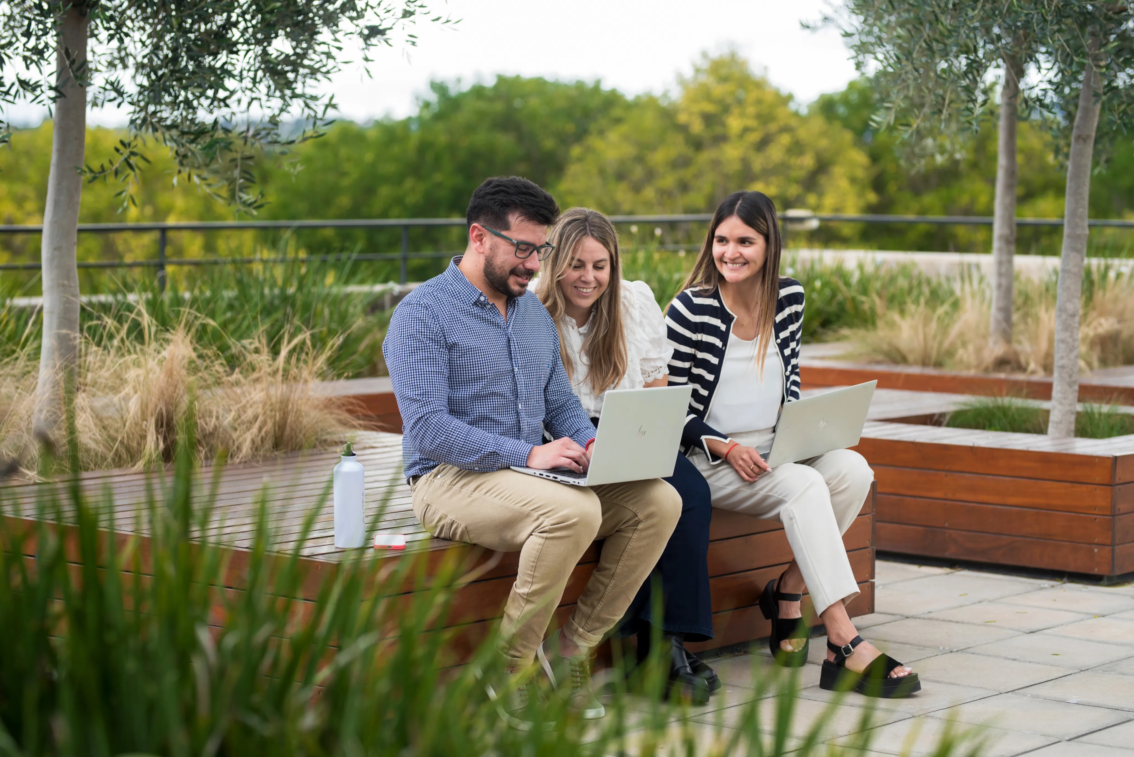Tres personas mirando una computadora en el patio exterior de una oficina